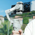 Hand hält einen Swevix Gimbal mit Smartphone vor klarem Himmel und unscharfem Hintergrund