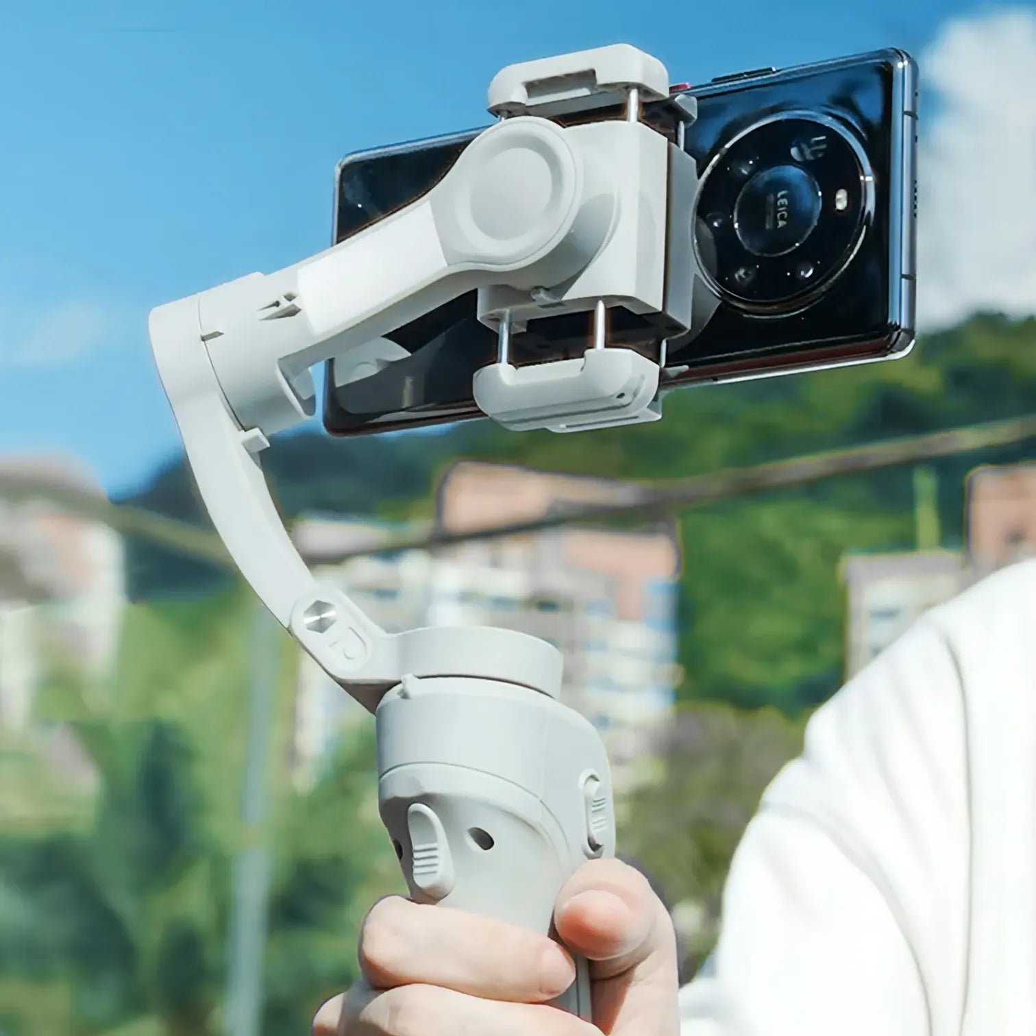 Hand hält einen Swevix Gimbal mit Smartphone vor klarem Himmel und unscharfem Hintergrund