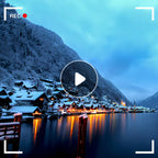 Snowy mountain village reflected in a lake with a play button overlay