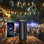 Smartphone und kabelloser Meacode tragbarer Bluetooth-Lautsprecher auf einem Holztisch mit unscharfem Hintergrund einer Gartenparty