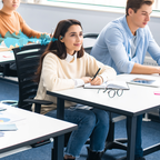 Studenten in einem Klassenzimmer, ein Student macht Notizen und hört über Meacode AI Translation Earbuds
