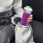 Person hält einen violetten Swevix Tragbarer Mixer mit weißer Basis und sitzt auf einem grauen Sofa