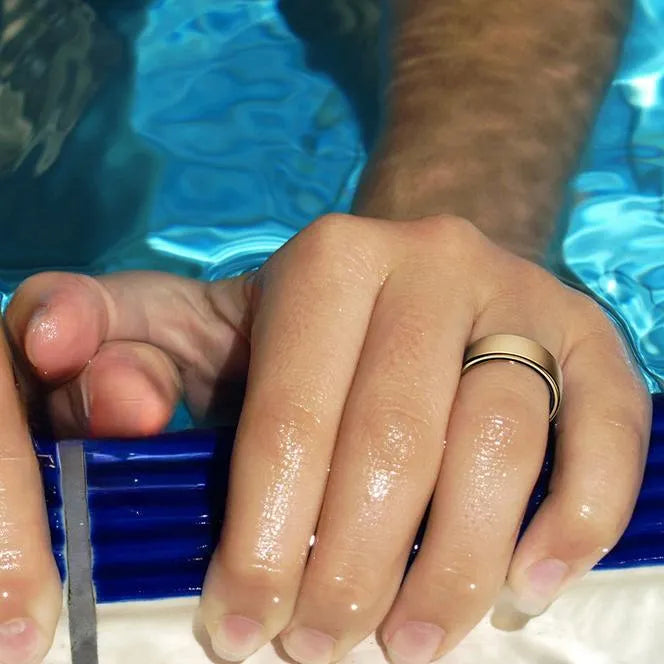 Nahaufnahme von Händen mit blauem Poolnudel und Wassertropfen auf der Haut vor blauem Poolhintergrund